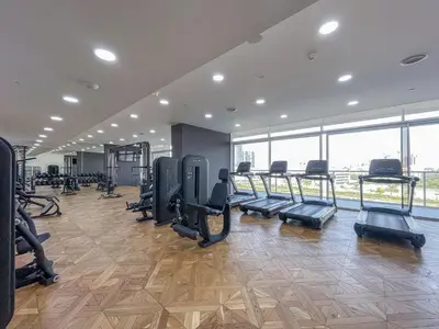 a gym with treadmills and ellipticals in a room with windows at Elegant 1br in Zaya Hameni in Dubai