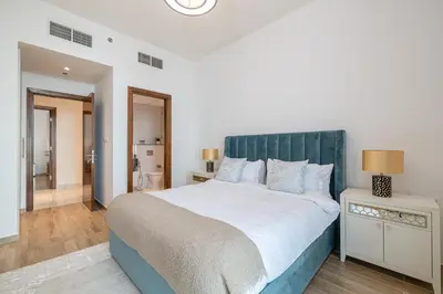 a bedroom with a large bed with a green headboard at Noora Tower I Spacious 3BDR Apartment and maid room with Burj Khalifa View in Dubai