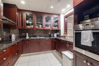 a kitchen with wooden cabinets and a stove top oven at 1 Bedroom at Yansoon 4, Downtown Old Town with Garden View in Dubai