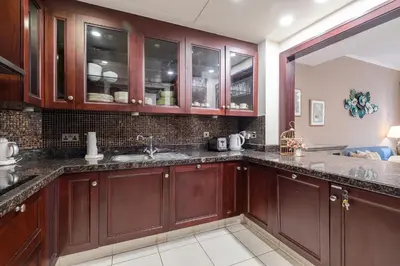 a kitchen with wooden cabinets and granite counter tops at 1 Bedroom at Yansoon 4, Downtown Old Town with Garden View in Dubai