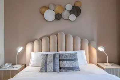 a bed with a large padded headboard and two lamps at 1 Bedroom at Yansoon 4, Downtown Old Town with Garden View in Dubai