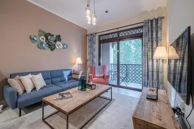 a living room with a blue couch and a table at 1 Bedroom at Yansoon 4, Downtown Old Town with Garden View in Dubai