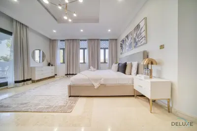 a white bedroom with a bed and a table and a mirror at Signature 6BR Villa with Assistant Room and Private Pool in Frond F Palm Jumeirah by Deluxe Holiday Homes in Dubai