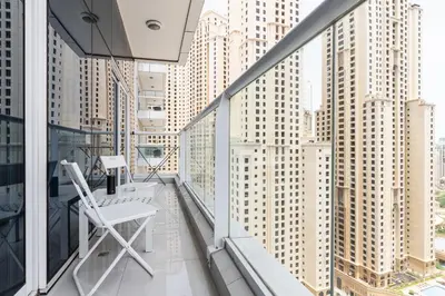 a white chair on a balcony with tall buildings at Amazing Marina View - Near the Beach! in Dubai