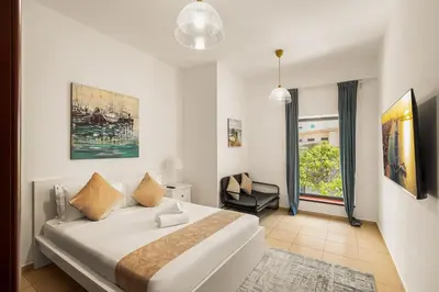 a bedroom with a large white bed and a chair at Beautiful 2BR & 4BR Apartments on JBR Beach, Walking Distance to Bluewaters Island - By Sunkissed Holiday Homes in Dubai
