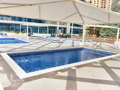 a pool with chairs and an umbrella next to a building at Beach apartment in Dubai in Dubai