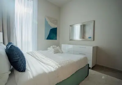 a white bedroom with a bed and a window at Nasma Luxury Stays - Harbour Gate Tower 1 in Dubai