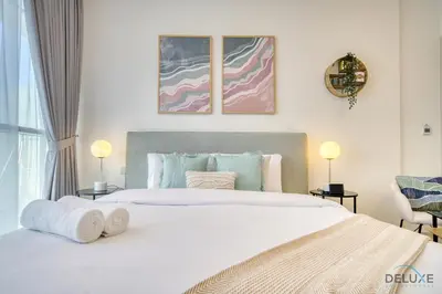 a bedroom with a large white bed with two lamps at Calm Studio at Carson C DAMAC Hills Dubailand by Deluxe Holiday Homes in Dubai