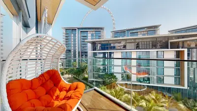 an orange chair on a balcony with a view of a city at Bluewaters Island 2 and 1 BDR Apart with Sea Views in Dubai