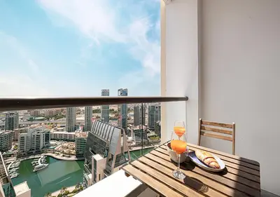 a balcony with a wooden table with a glass of wine at Luxury Beachfront 2Bd Apt, Shams, JBR in Dubai