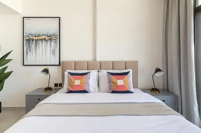 a bedroom with a bed with pillows and two lamps at Frank Porter - Binghatti Avenue in Dubai
