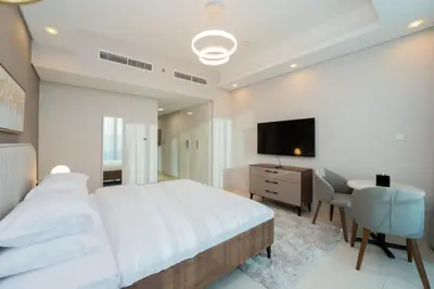 a bedroom with a bed and a desk and a television at Kasco Homes Waves Tower Business Bay in Dubai