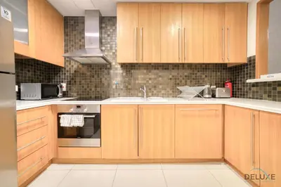 a kitchen with wooden cabinets and a sink at Hot Deal Modern 1BR at Iris Blue, Don't Miss Out by Deluxe Holiday Homes in Dubai