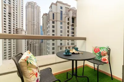 a small table and chairs on a balcony with buildings at Ultimate Stay 2BR Sea View at JBR Beach Ain Dubai High Floor Luxury Stay in Dubai