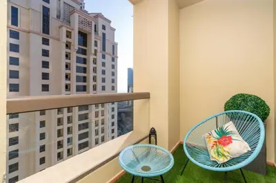 a balcony with two chairs and a bag of fruit at Ultimate Stay 2BR Sea View at JBR Beach Ain Dubai High Floor Luxury Stay in Dubai