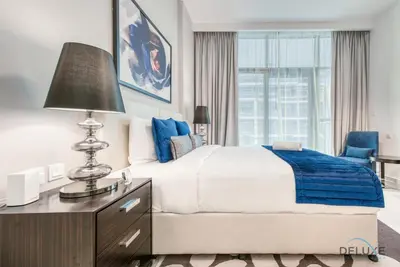 a bedroom with a bed and a desk with a lamp at Luxuriant Studio at Golf Promenade 2A DAMAC Hills by Deluxe Holiday Homes in Dubai