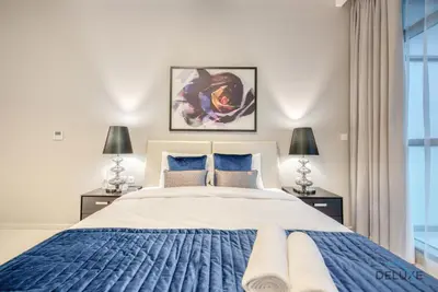 a bedroom with a large bed and two lamps at Stunning Studio at Golf Promenade 2A Damac Hills by Deluxe Holiday Homes in Dubai