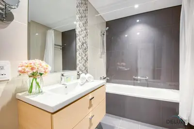a bathroom with a sink and a tub and a vase of flowers at Stunning Studio at Golf Promenade 2A Damac Hills by Deluxe Holiday Homes in Dubai