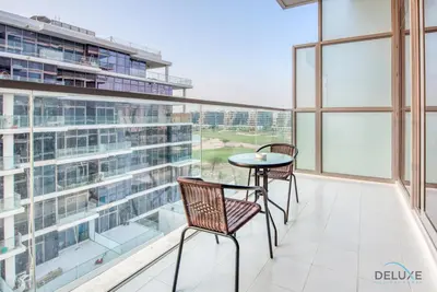 a balcony with two chairs and a table at Stunning Studio at Golf Promenade 2A Damac Hills by Deluxe Holiday Homes in Dubai