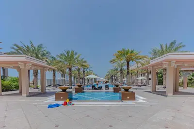 a resort courtyard with palm trees and a swimming pool at Fully-equppied studio with private beach and pool in Dubai