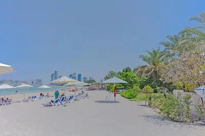 a beach with people sitting on chairs and umbrellas at Fully-equppied studio with private beach and pool in Dubai