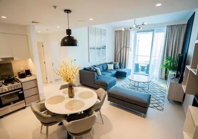 a living room with a table and a blue couch at Nasma Luxury Stays - The Grand, Dubai Creek Harbour in Dubai