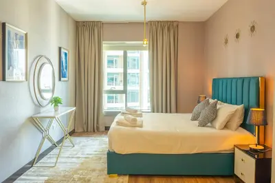 a bedroom with a bed with a blue headboard and a window at BellaVista 29 Boulevard 1 Bedroom Apartment with Extra Bedroom Partial Fountain Views in Dubai