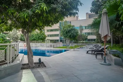 a pool with chairs and an umbrella next to a building at BellaVista 29 Boulevard 1 Bedroom Apartment with Extra Bedroom Partial Fountain Views in Dubai