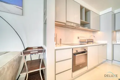 a kitchen with white cabinets and a staircase at Splendid 2BR at Sunrise Bay Tower 1 Emaar Beachfront Dubai Marina by Deluxe Holiday Homes in Dubai