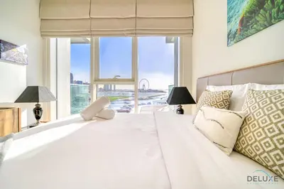 a bedroom with a large white bed with a large window at Splendid 2BR at Sunrise Bay Tower 1 Emaar Beachfront Dubai Marina by Deluxe Holiday Homes in Dubai