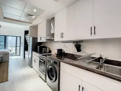 a kitchen with white cabinets and a sink and a dishwasher at Luxury Modern Studio in JLT - Rooftop Pool - Lake Area Upgrades Ongoing in Dubai