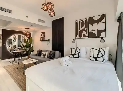a bedroom with a large white bed and a living room at Luxury Modern Studio in JLT - Rooftop Pool - Lake Area Upgrades Ongoing in Dubai