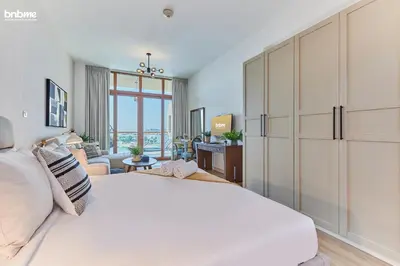 a bedroom with a large white bed and a living room at bnbme - Palm Jumeirah Studio Balcony Sea Ain Dubai Views Pool Gym Parking Access in Dubai