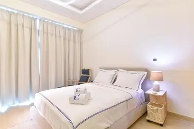 a bedroom with a white bed and a large window at Luxury Escapes - Brand New Studio with View - Azizi Farhad Jaddaf in Dubai