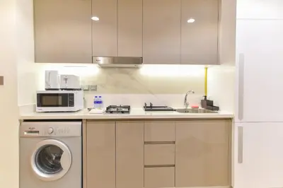 a kitchen with a washing machine and a microwave at Luxury Escapes - Brand New Studio with View - Azizi Farhad Jaddaf in Dubai