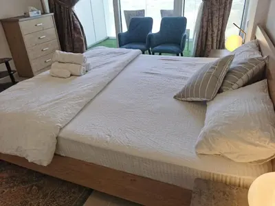 a large bed in a bedroom with two blue chairs at Gharfar-2 Heaven Escape-Golf view-high floor-Netflix-GYM-Pool-perfect staycation in Dubai