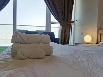 a bedroom with a white bed with a large window at Gharfar-2 Heaven Escape-Golf view-high floor-Netflix-GYM-Pool-perfect staycation in Dubai