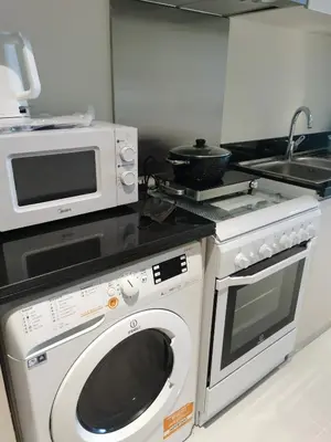 a kitchen with a microwave and a washing machine at Gharfar-2 Heaven Escape-Golf view-high floor-Netflix-GYM-Pool-perfect staycation in Dubai