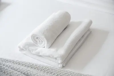a roll of white towels sitting on top of a bed at Gorgeous One Bedroom Apartment in the heart of Dubai in Dubai