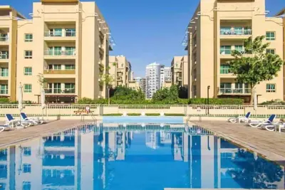 a swimming pool with chairs and some buildings at Gorgeous One Bedroom Apartment in the heart of Dubai in Dubai