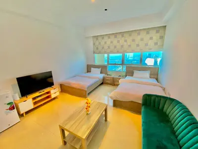 a room with two beds and a couch and a tv at Marina Crown Tower Stays Hostel for Girls in Dubai