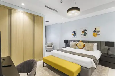 a bedroom with a large bed and a yellow bench at ALiving Luxury 2BR with Infinity Pool I Near Dubai Mall & Burj Khalifa I Paramount Hotel Midtown in Dubai