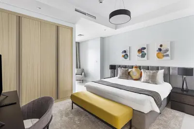 a bedroom with a large bed and a yellow bench at ALiving Luxury 2BR with Infinity Pool I Near Dubai Mall & Burj Khalifa I Paramount Hotel Midtown in Dubai