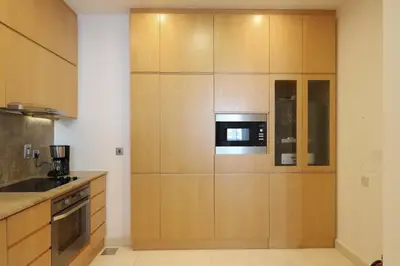a kitchen with wooden cabinets and a microwave at Livbnb Suites - 1BR with Sea View & Beach Access in Dubai