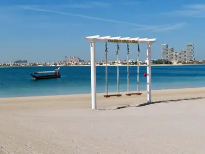 a white structure on a beach with a boat in the water at Lovely 1 bedroom apartment at 5 Star Resort in Dubai