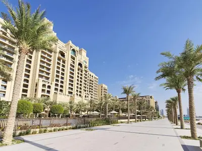 a street with palm trees in front of a large building at Fairmont The Palm Residences I Access to Hotel Facilities in Dubai