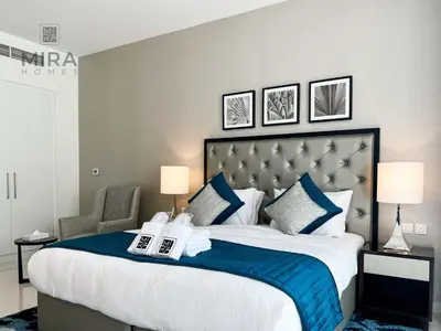 a bedroom with a large bed with blue and white pillows at Mira Holiday Homes - Newly serviced apartment in Dubai South in Dubai
