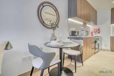 a table and chairs in a kitchen with a mirror at Placid 1BR at La Cote 5 Jumeirah 1 by Deluxe Holiday Homes in Dubai