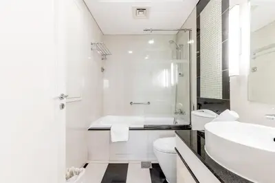 a white bathroom with a tub and a sink at Damac Mall Street Residences in Dubai