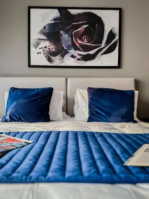 a bed with blue pillows and a painting on the wall at Trophy Stays - Peaceful Golf side Escape Studio - Damac Hills in Dubai